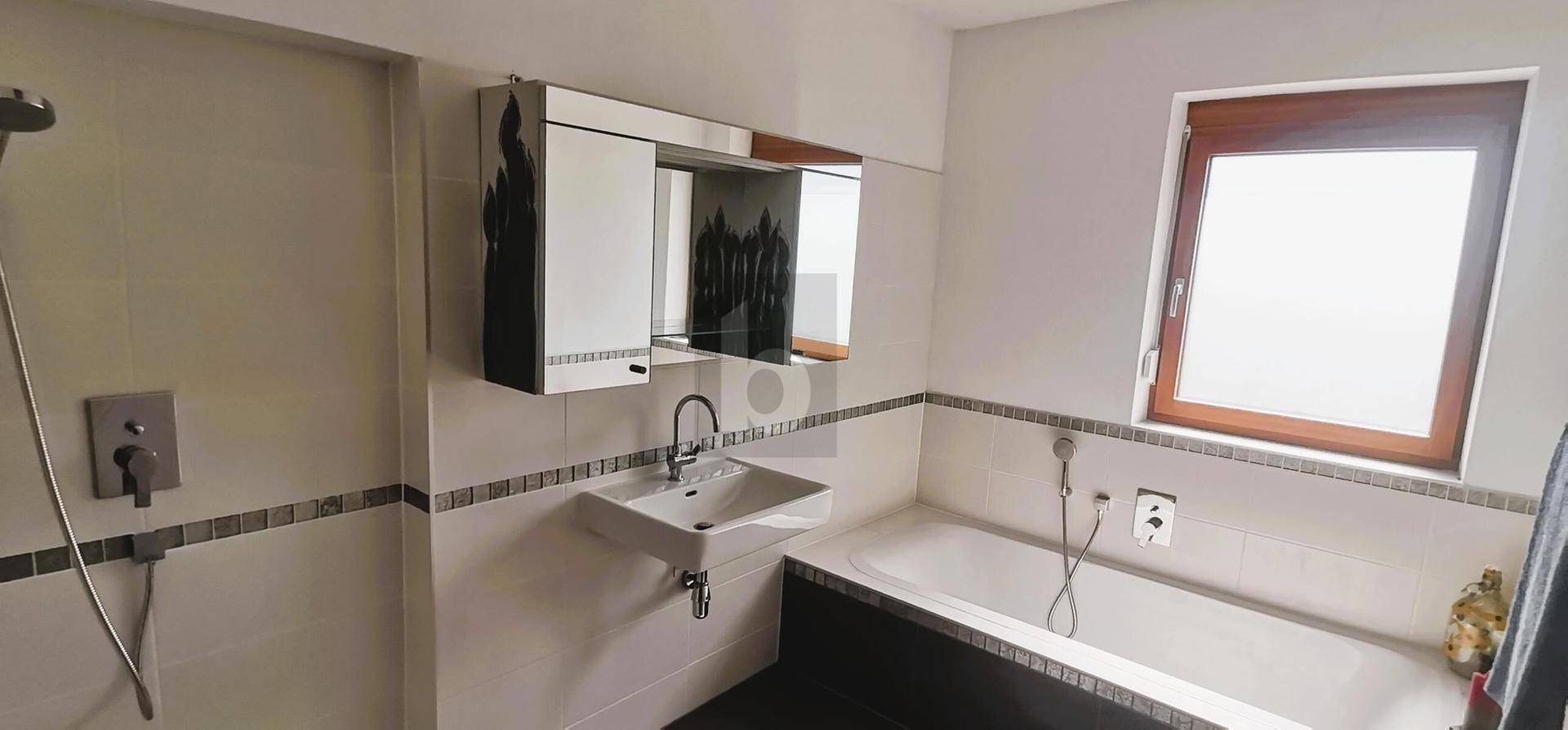 Modernes Badezimmer mit Badewanne, Duschbereich, Einzelwaschbecken und Fenster.