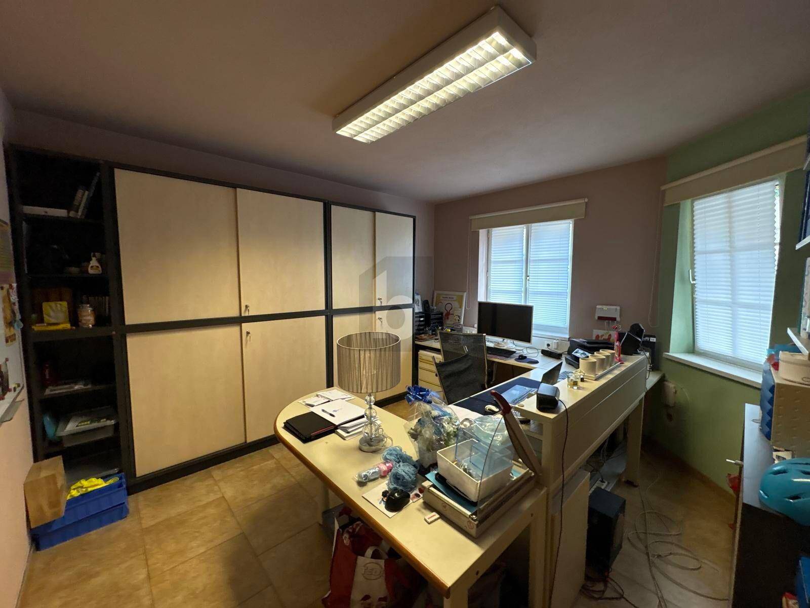 Funktionales Büro mit Einbauschränken, Schreibtischen und Fenstern.