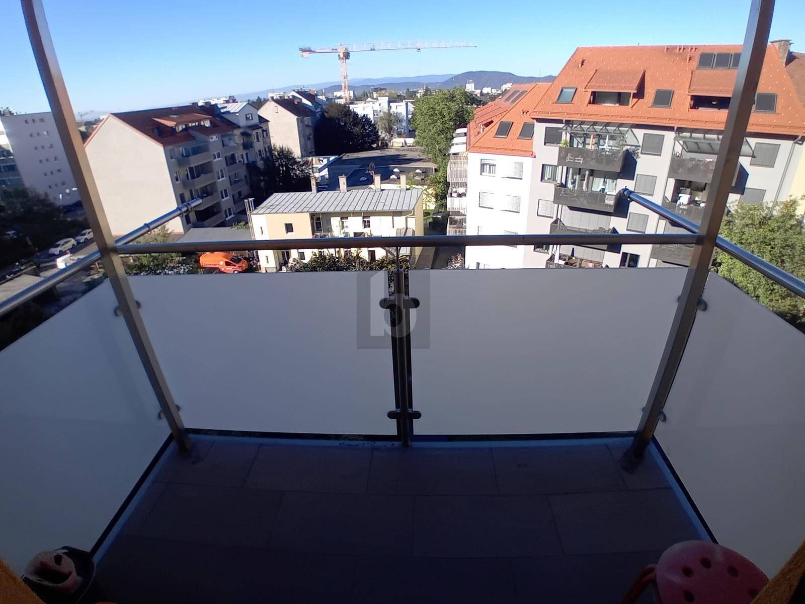 Blick vom Balkon auf die umliegende Wohngegend mit Gebäuden und einem Kran am Horizont.