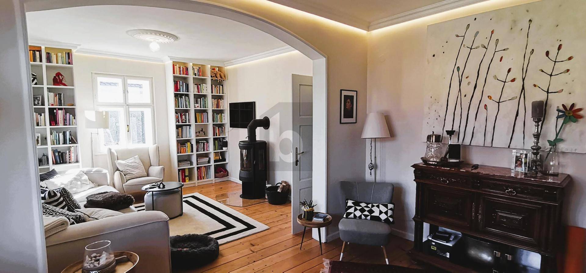 Gemütliches Wohnzimmer mit Holzboden, Bücherregalen und einem Kaminofen in offener Gestaltung.