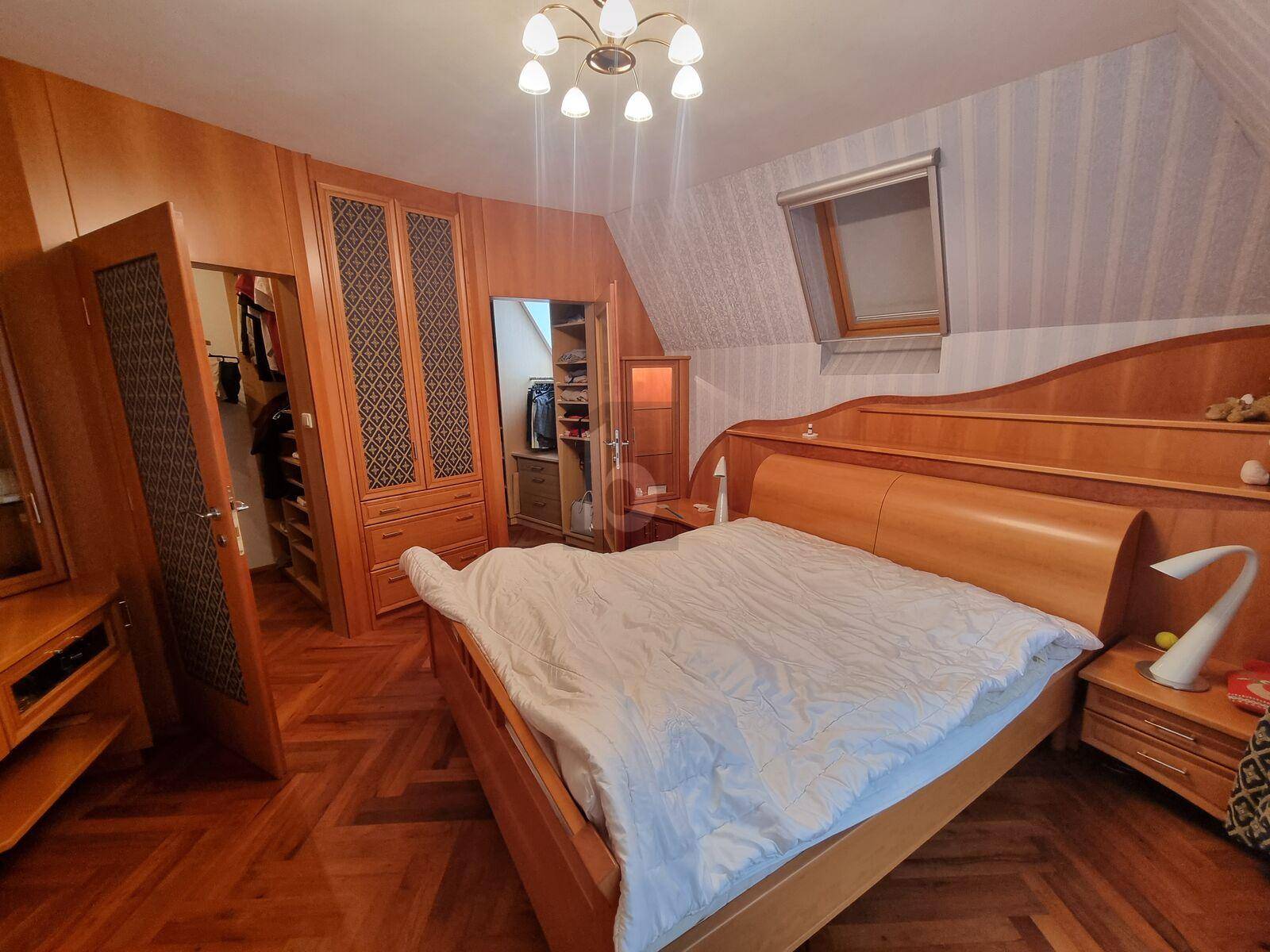 Gemütliches Schlafzimmer mit Holzmöbeln, Parkettboden und Dachschrägenfenster.