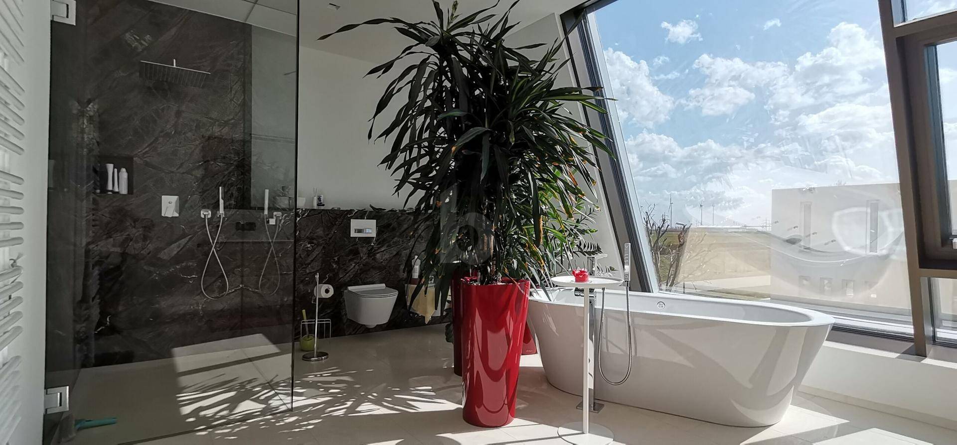 Luxuriöses Badezimmer mit freistehender Badewanne, großer Dusche und viel Tageslicht.