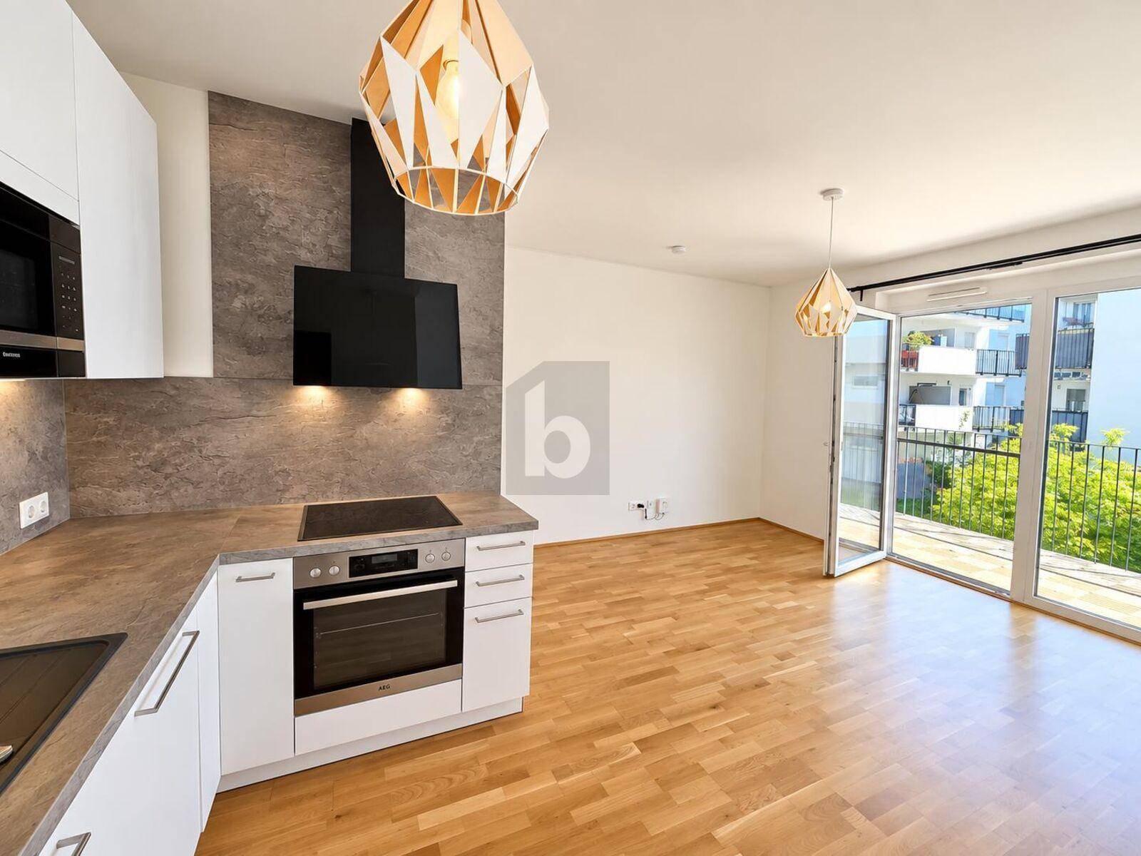 Offener Wohnbereich mit moderner Küche, Parkettboden und Zugang zum Balkon.