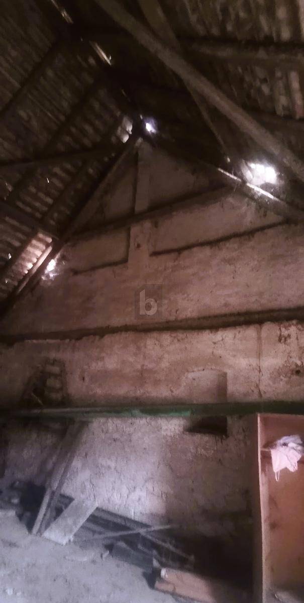 Verfallener Dachboden mit sichtbaren Holzbalken und beschädigtem Dach, das Tageslicht hereinlässt.