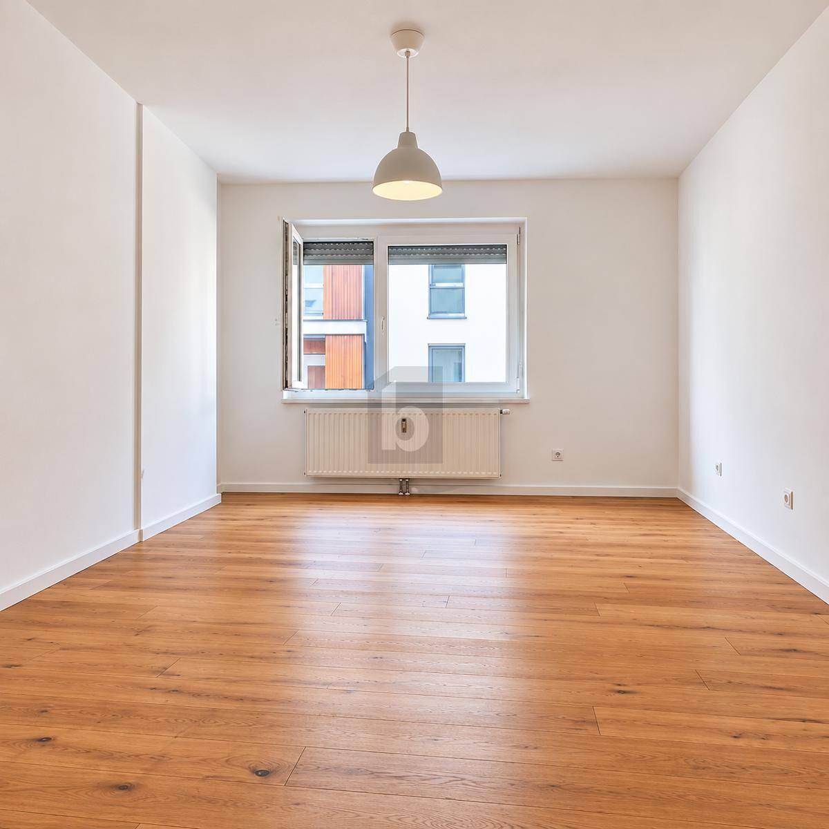 Sauberer, heller Raum mit Holzboden, Fenster mit Rollladen und einfacher Deckenleuchte.