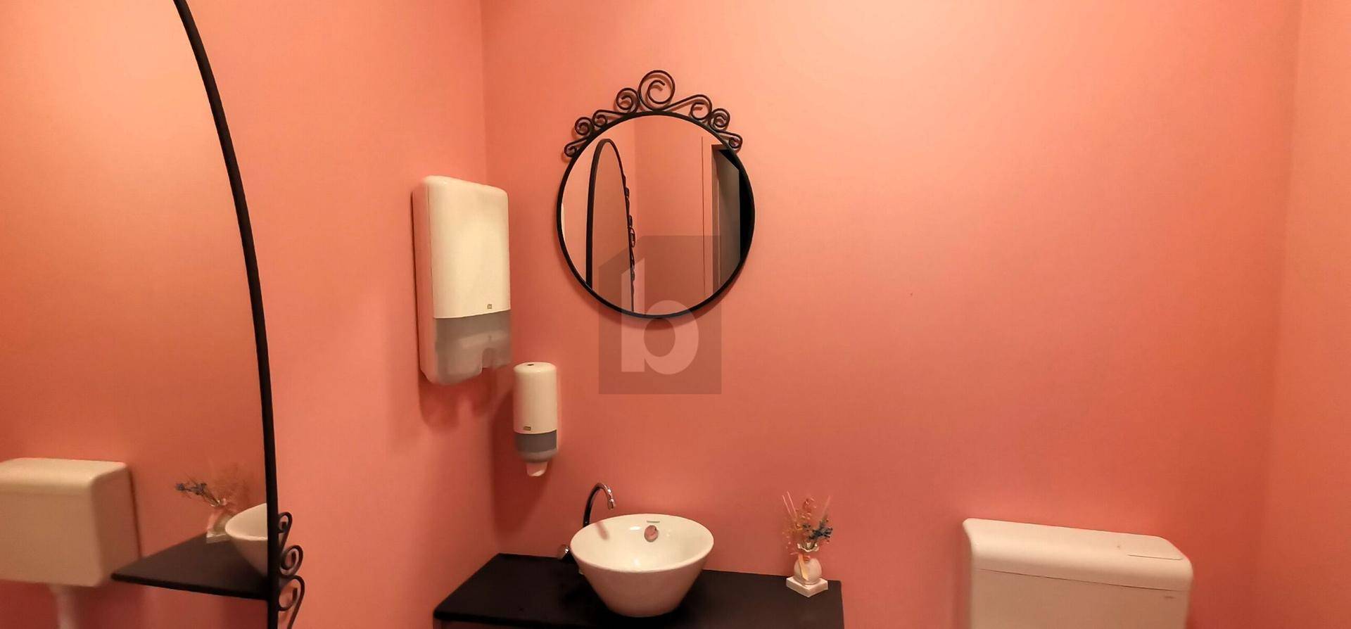 Modernes Gäste-WC mit rosa Wänden, einem runden Spiegel und einem stilvollen Waschbecken.