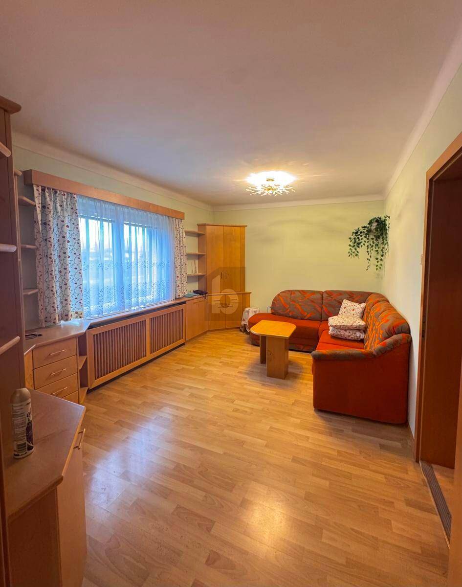 Gemütliches Wohnzimmer mit orangefarbenem Ecksofa, Holzmöbeln und Laminatboden.