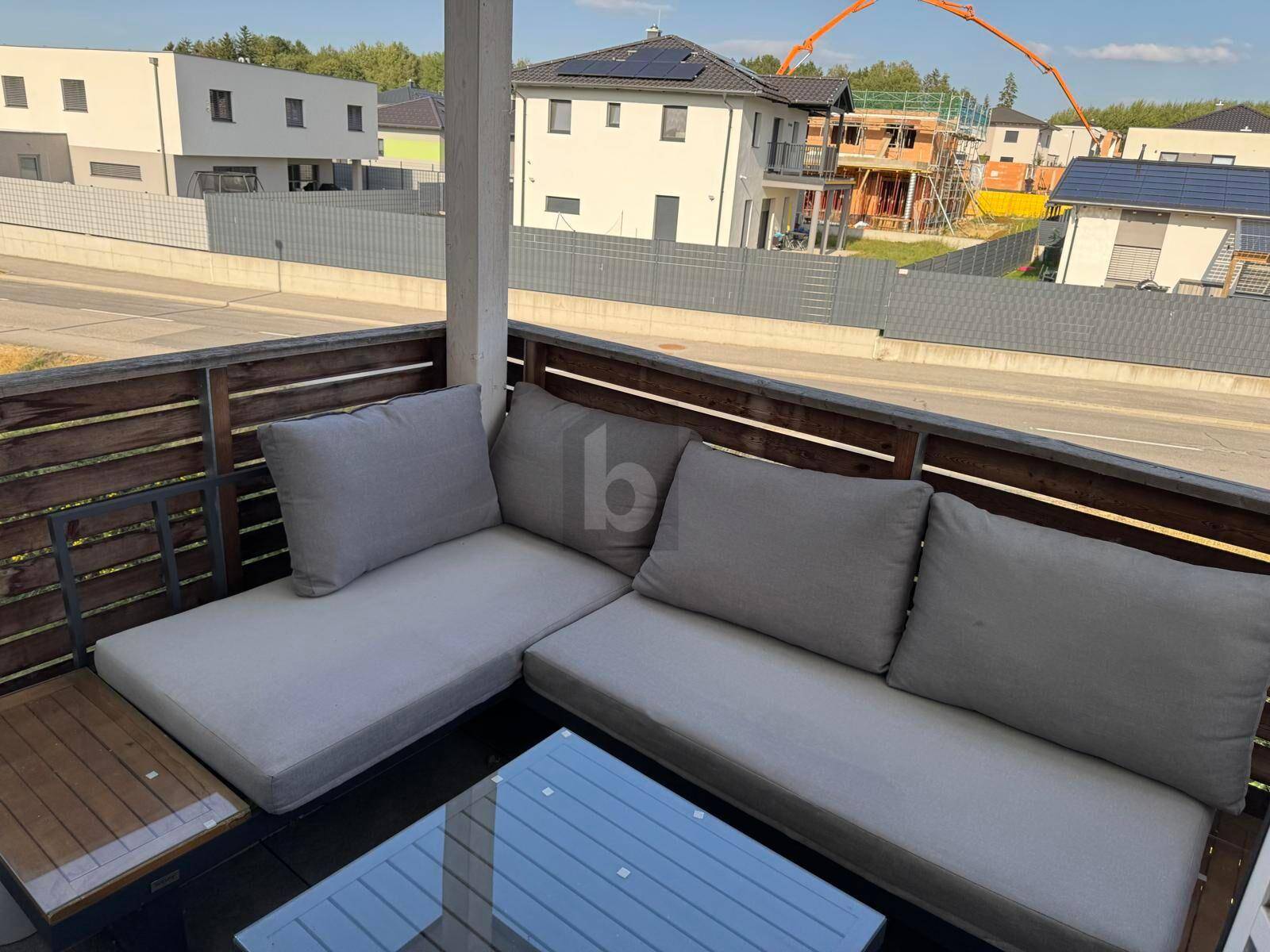 Gemütlicher Balkon mit bequemen Outdoor-Möbeln und Blick auf die Nachbarschaft.