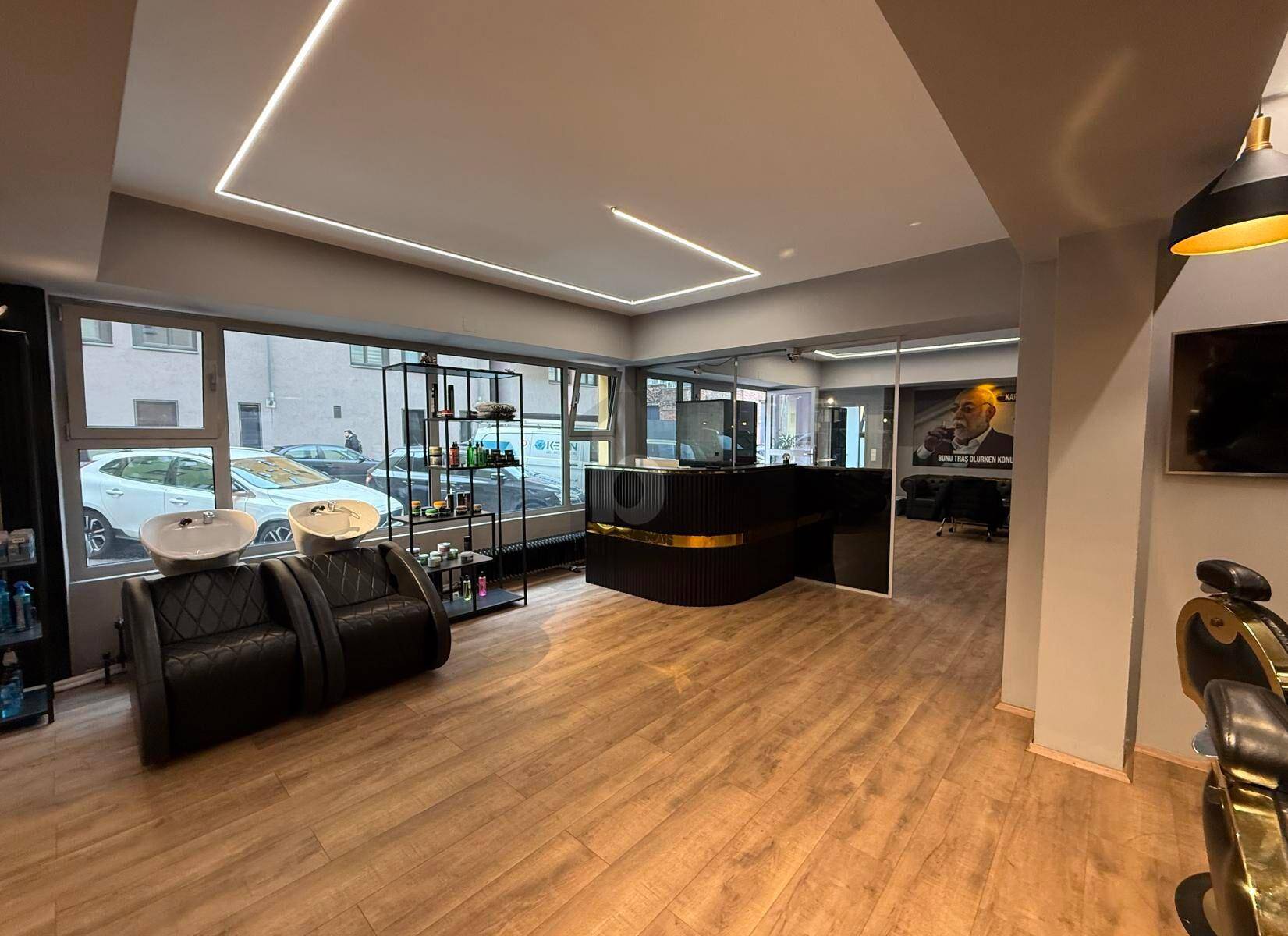 Geräumiger Friseursalon mit moderner Rezeption, Waschbecken und Blick auf die Straße.