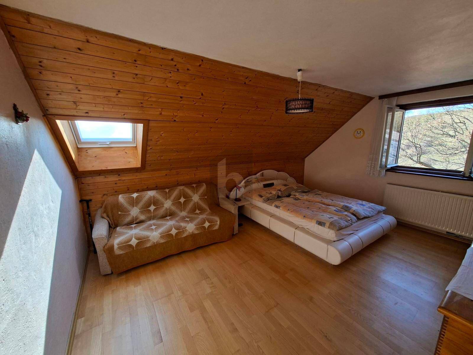 Gemütliches Schlafzimmer mit Holzvertäfelung, Dachschräge und Dachfenster für natürliches Licht.