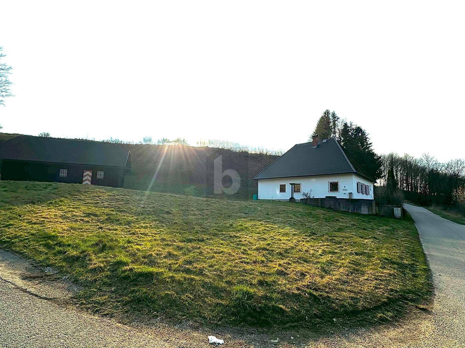 Sonnenbeschienene Ansicht des weißen Hauses und des Holzgebäudes in ländlicher Umgebung.