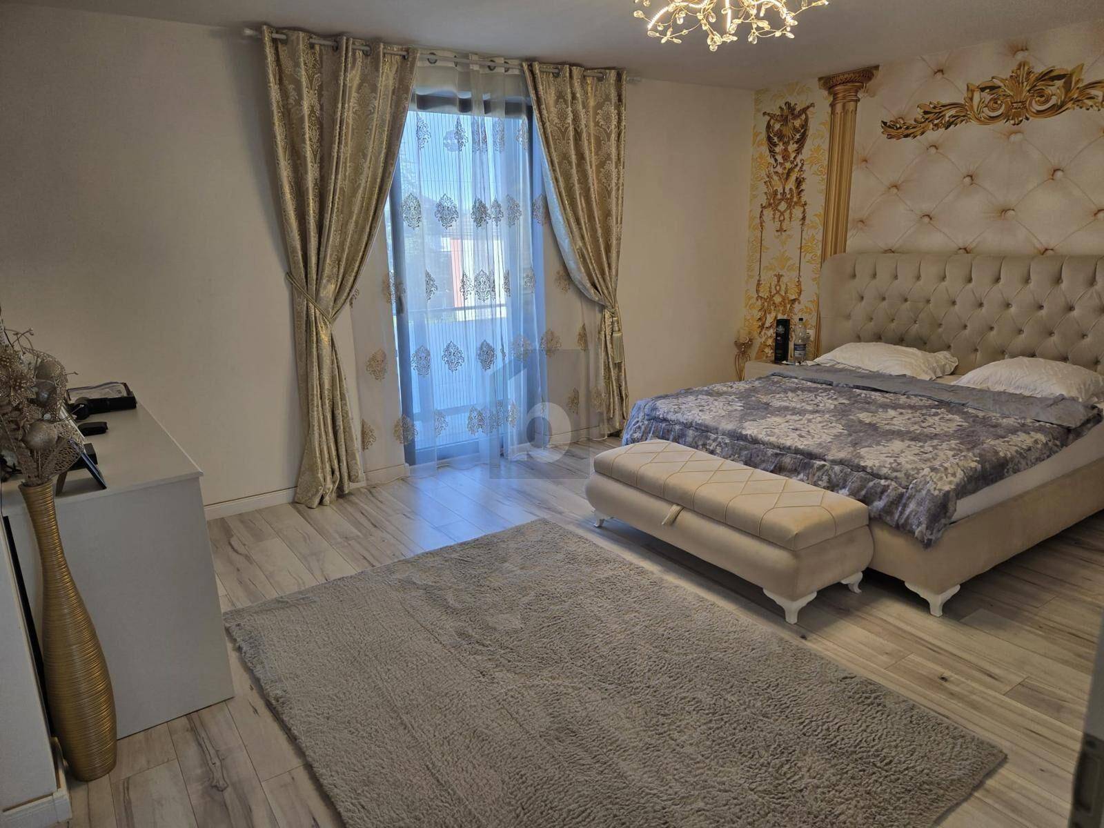 Geräumiges Schlafzimmer mit großem Bett, gepolstertem Kopfteil und eleganten Vorhängen, hell und modern eingerichtet.