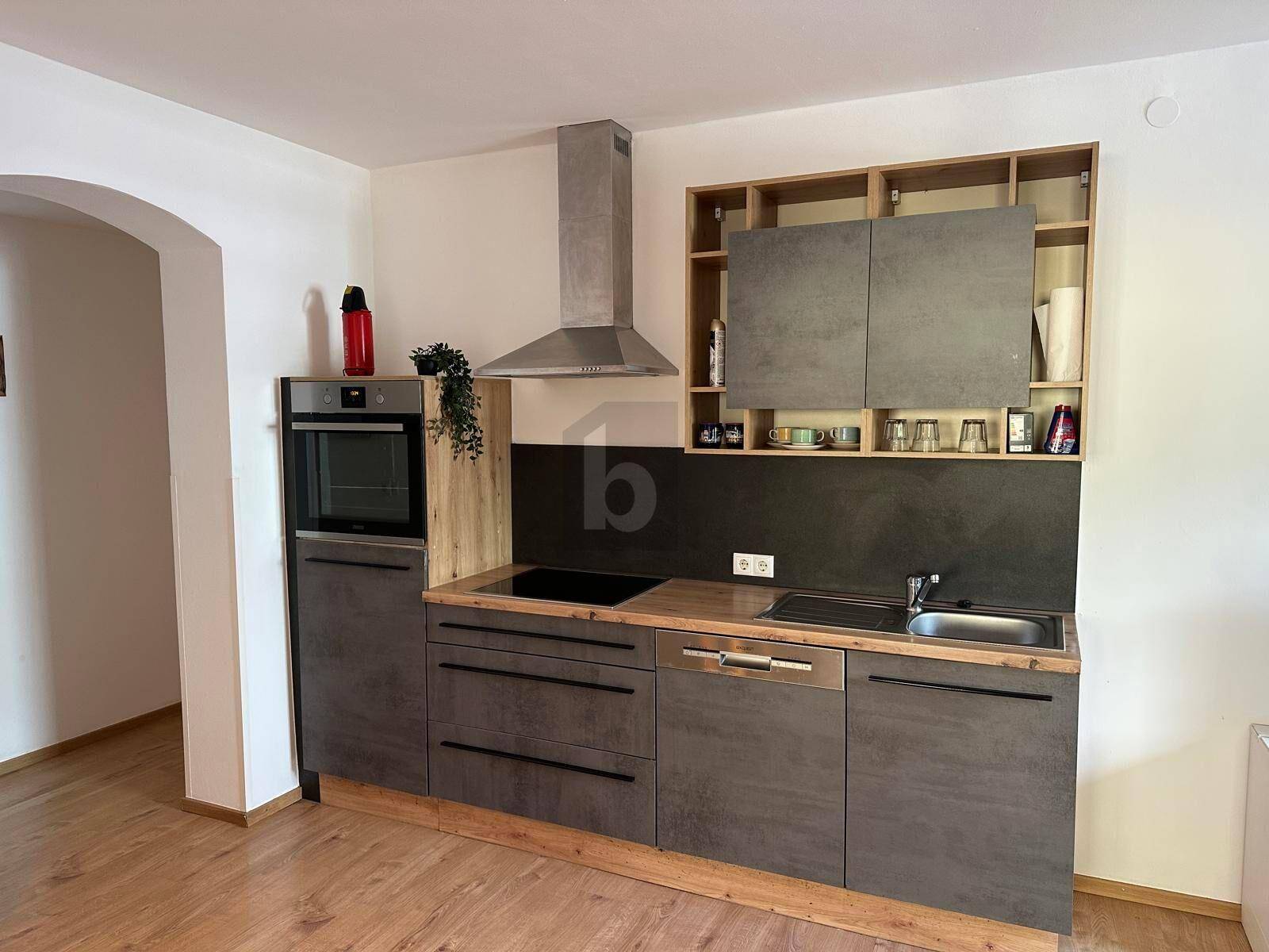 Moderne Einbauküche in Grau mit Holzarbeitsplatte, Spüle und integrierten Geräten.