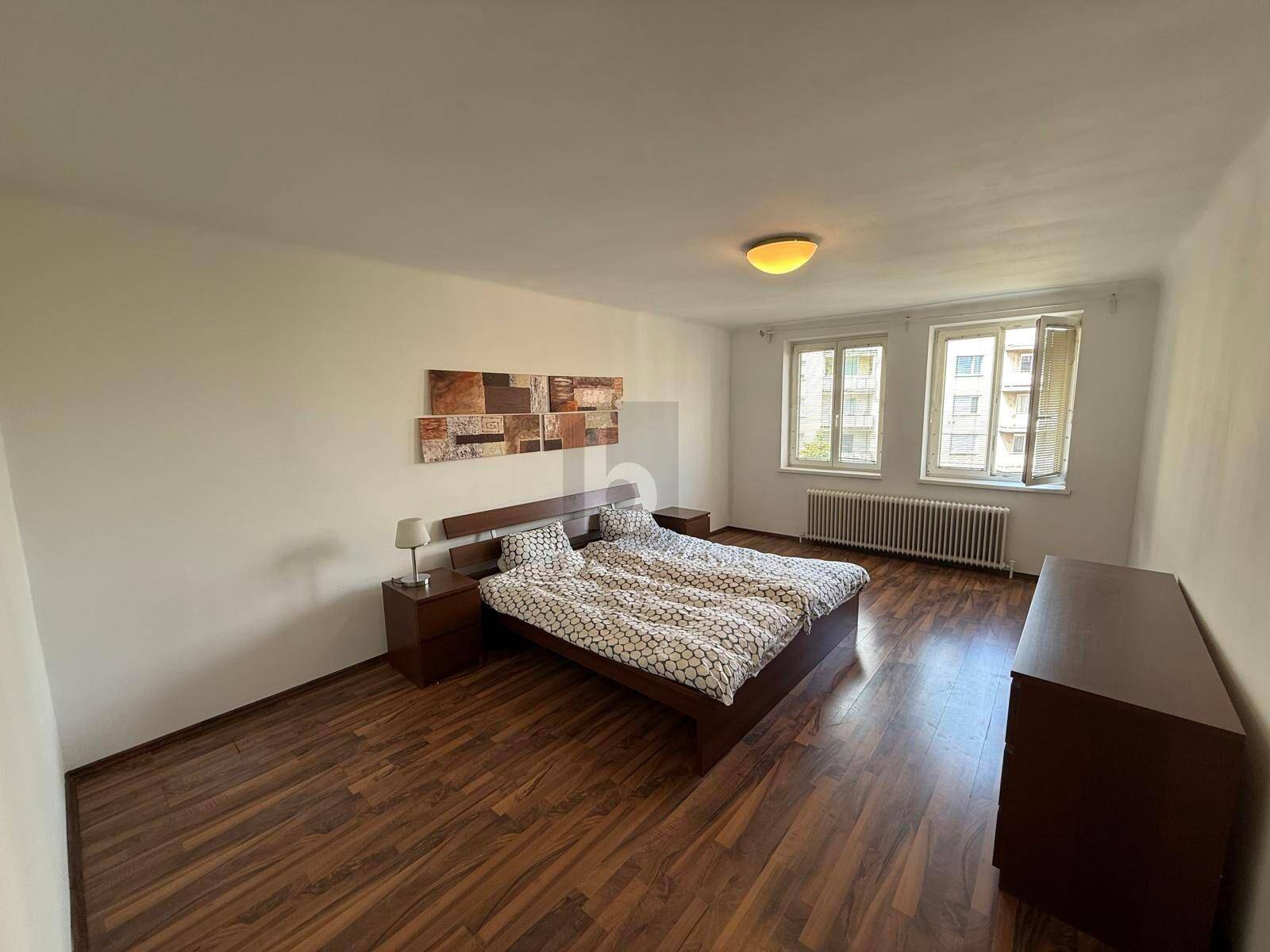 Helles Schlafzimmer mit Doppelbett, Nachttischen und Laminatboden.