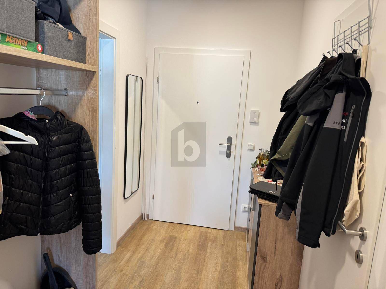 Eingangsbereich mit Garderobe, Spiegel und hellem Laminatboden.