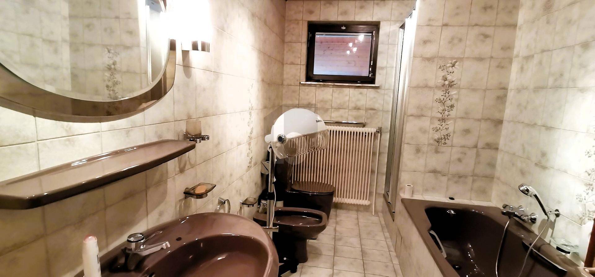 Badezimmer mit Badewanne, WC und Fliesen in neutralen Farbtönen.
