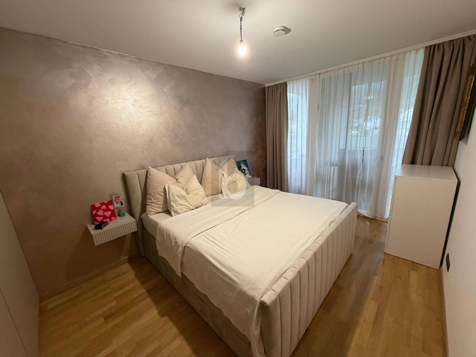 Helles Schlafzimmer mit großem Doppelbett, Holzboden und Vorhängen für Privatsphäre.