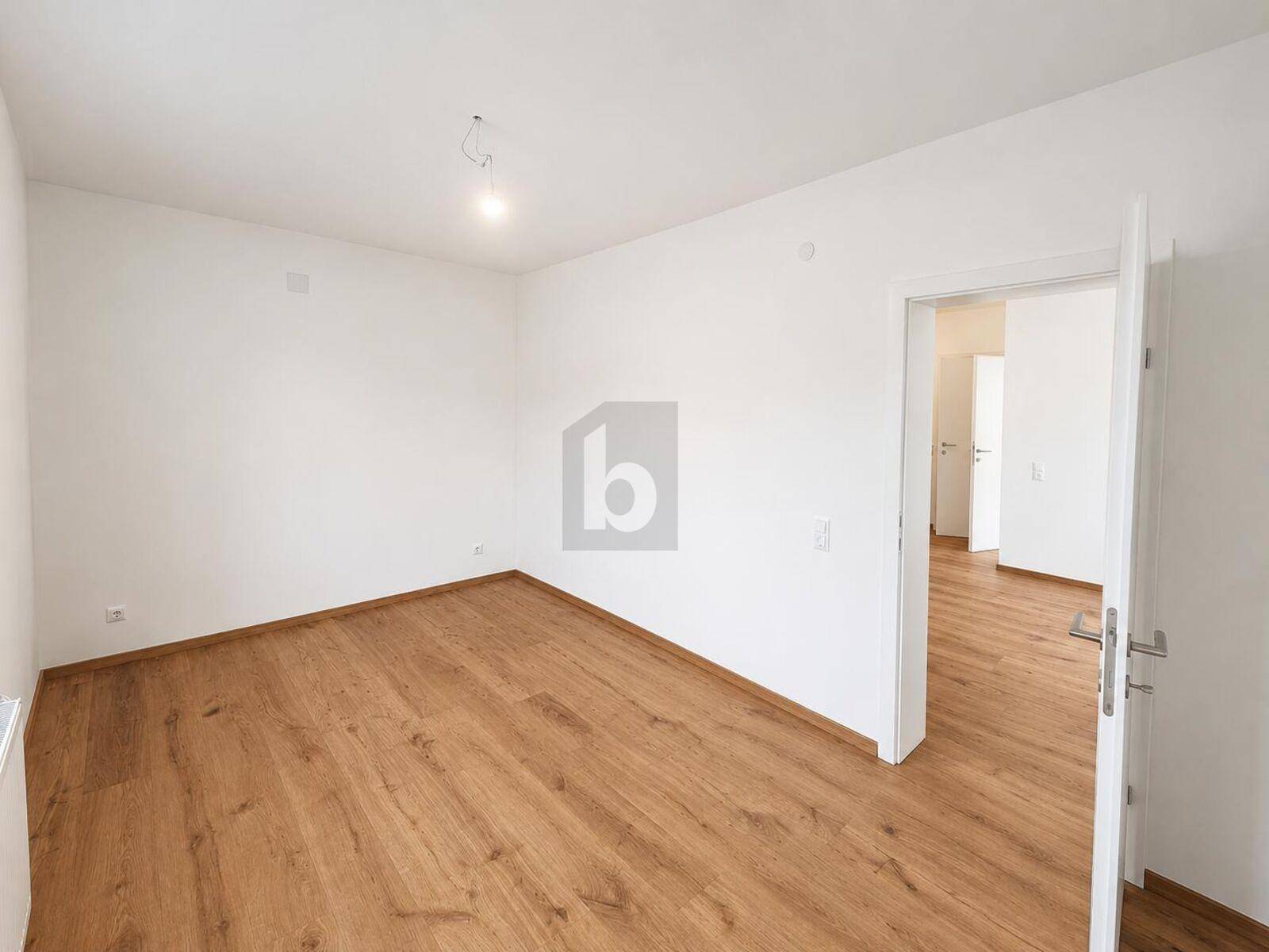 Lichtdurchflutetes Zimmer mit Holzboden und weiß gestrichenen Wänden, bereit zum Einzug.