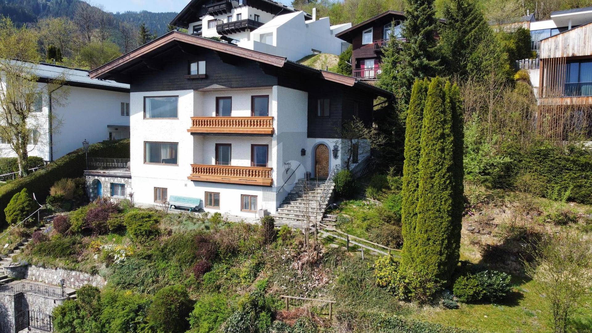 Charmantes Wohnhaus mit traditioneller Architektur, Holzbalkonen und gepflegter Außenanlage.