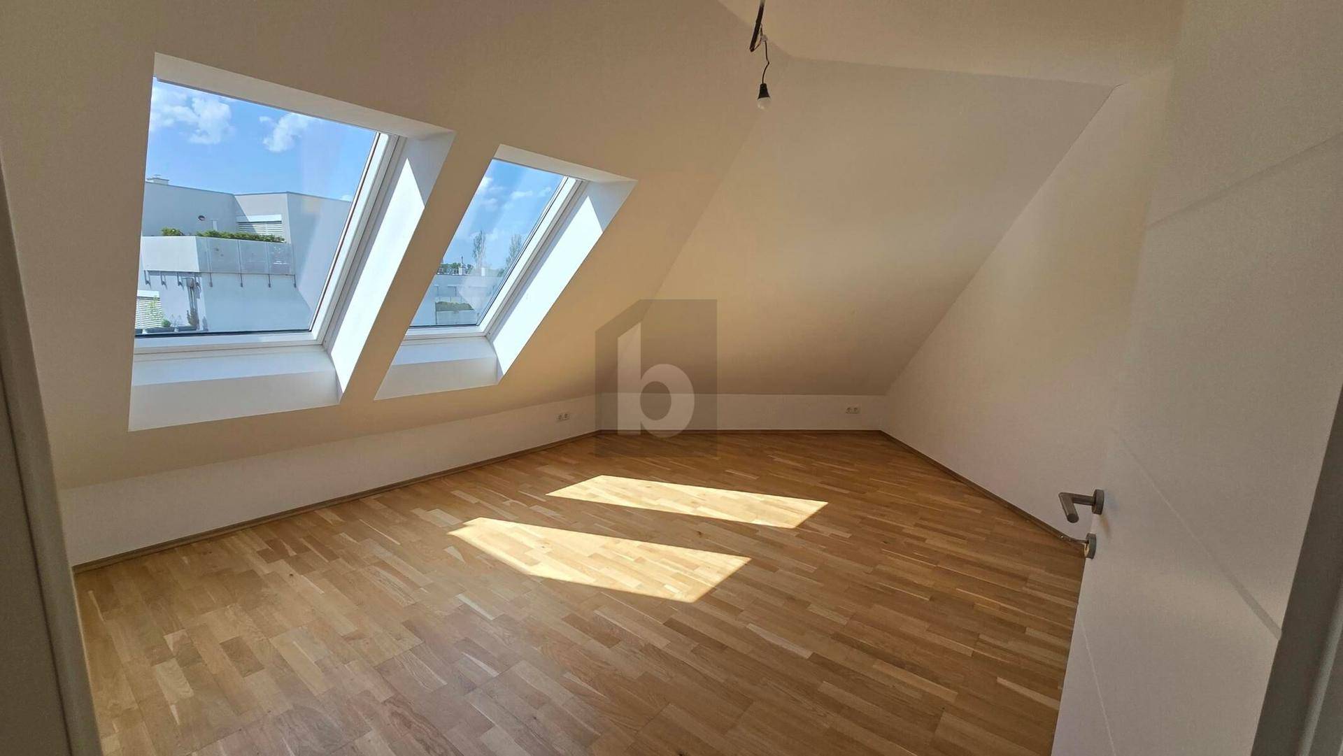 Helles Zimmer im Dachgeschoss mit drei großen Dachfenstern, Holzboden und viel natürlichem Licht.