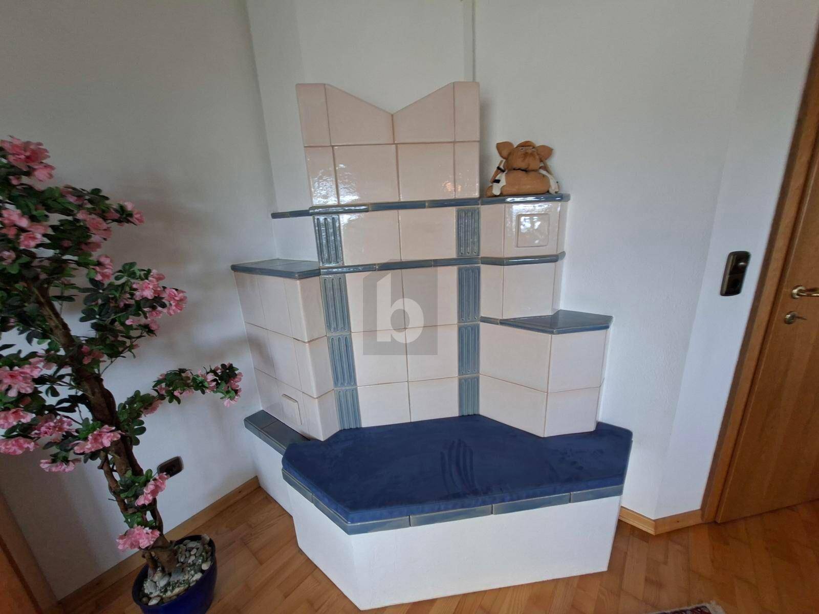 Traditioneller Kachelofen mit Sitzbank in einem gemütlichen Raum mit Holzfußboden.