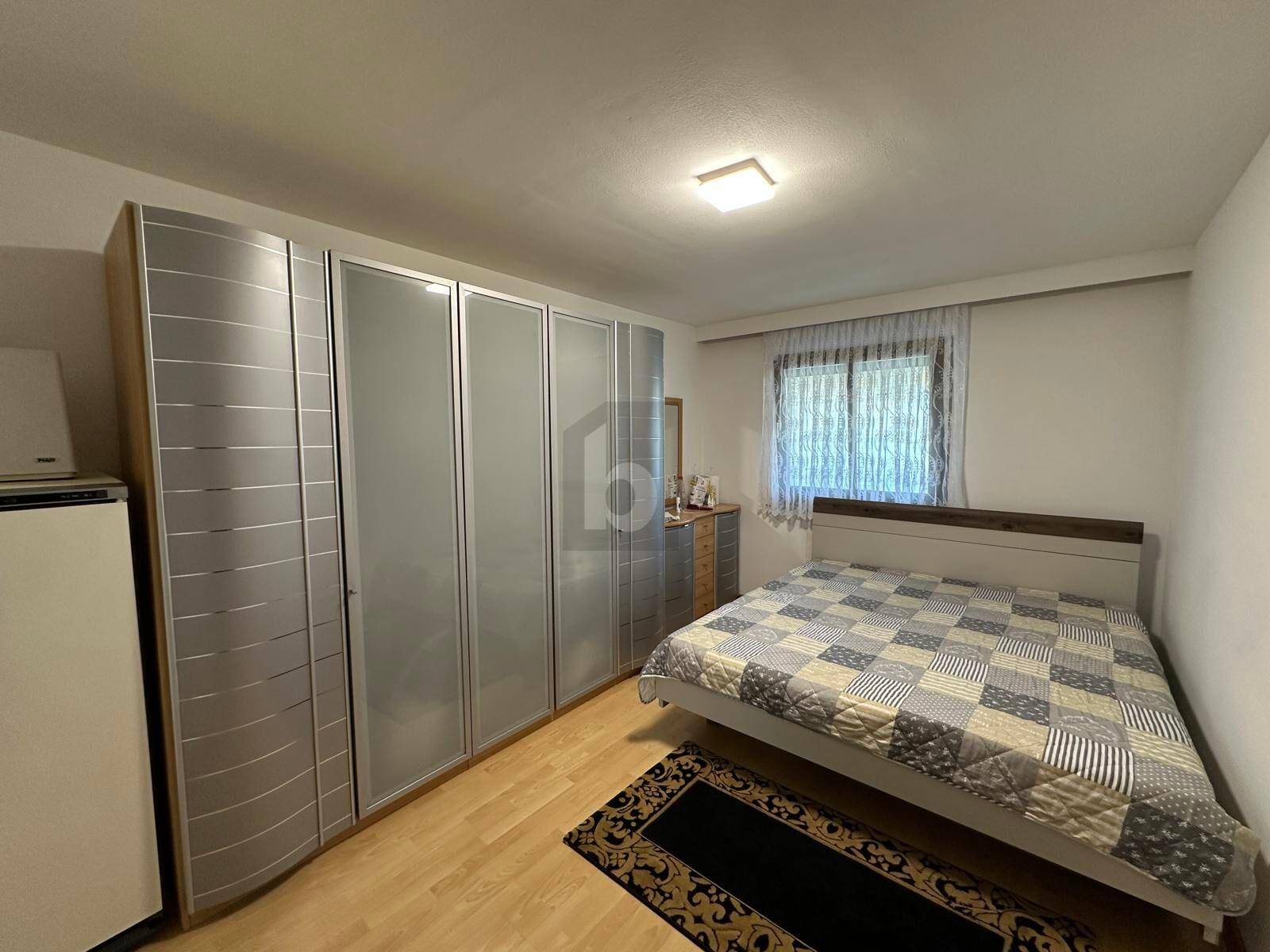Gemütliches Schlafzimmer mit Doppelbett, großem Kleiderschrank und hellem Parkettboden.