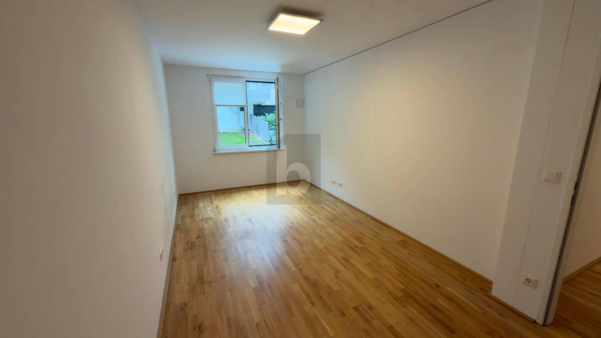 Gemütliches Zimmer mit Holzboden und einem Fenster, das viel Tageslicht hereinlässt.