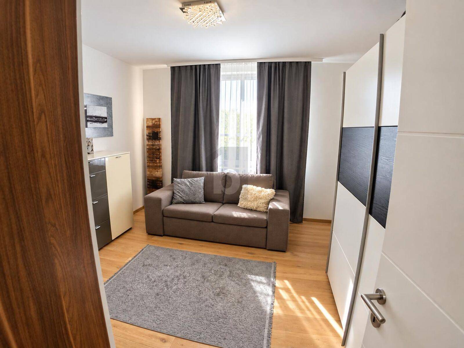 Gemütliches Zimmer mit Schlafsofa, Kleiderschrank und Holzboden, ideal als Gästezimmer.