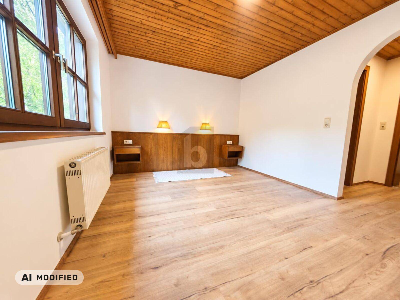 Geräumiges Schlafzimmer mit Holzboden, Holzdecke und Blick ins Grüne.