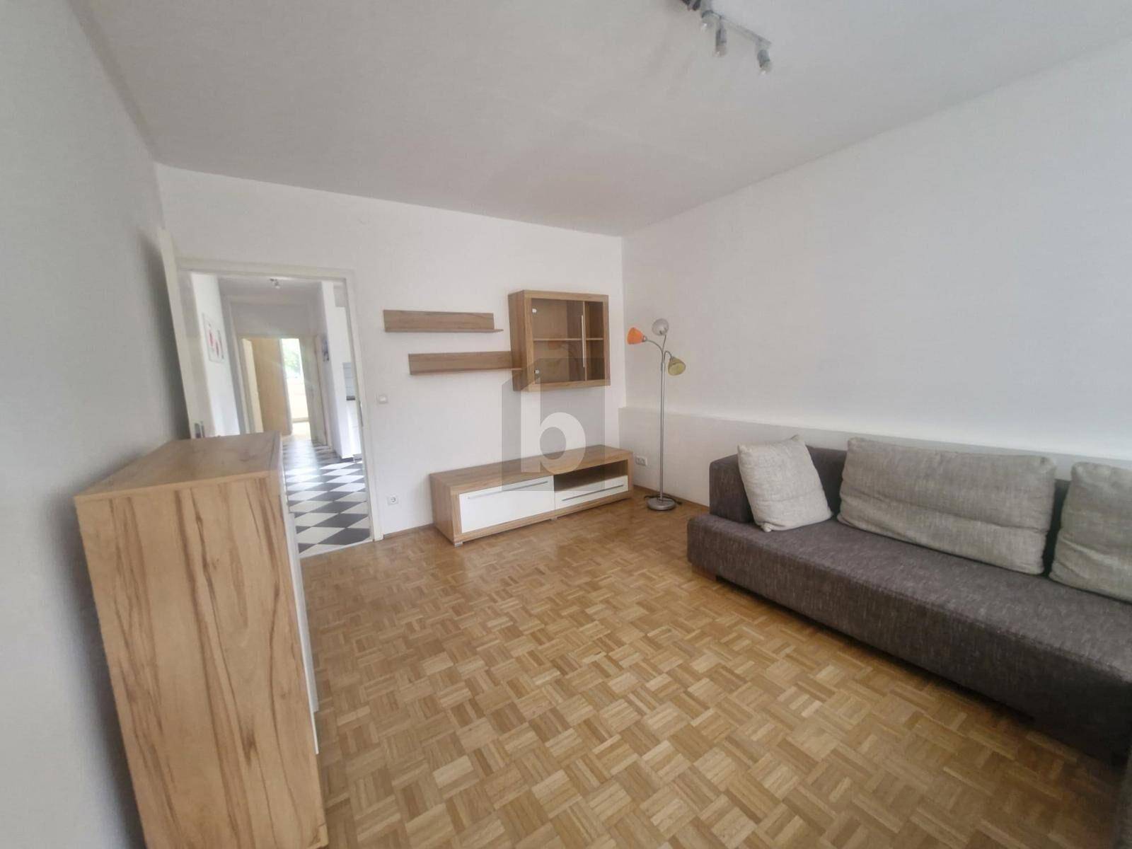 Wohnzimmer mit Parkettboden, Sofa und Blick in den Flur.