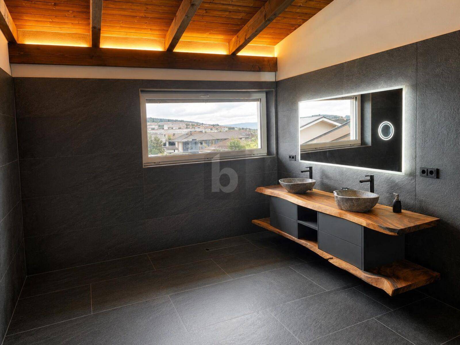 Modernes Badezimmer mit Doppelwaschbecken auf Holzplatte und dunklen Fliesen.