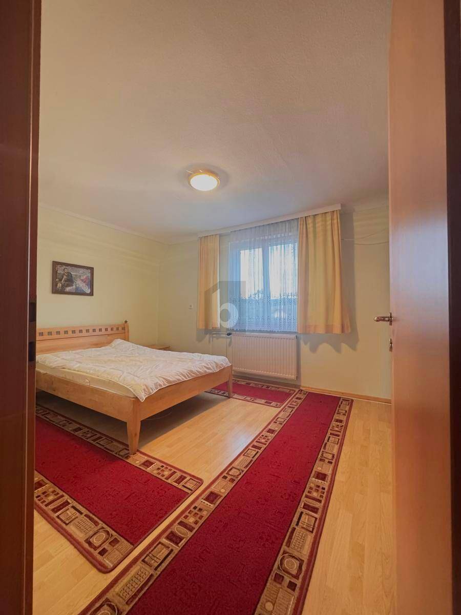 Schlafzimmer mit hellem Holzbett, Laminatboden und Fenster mit Blick nach draußen.