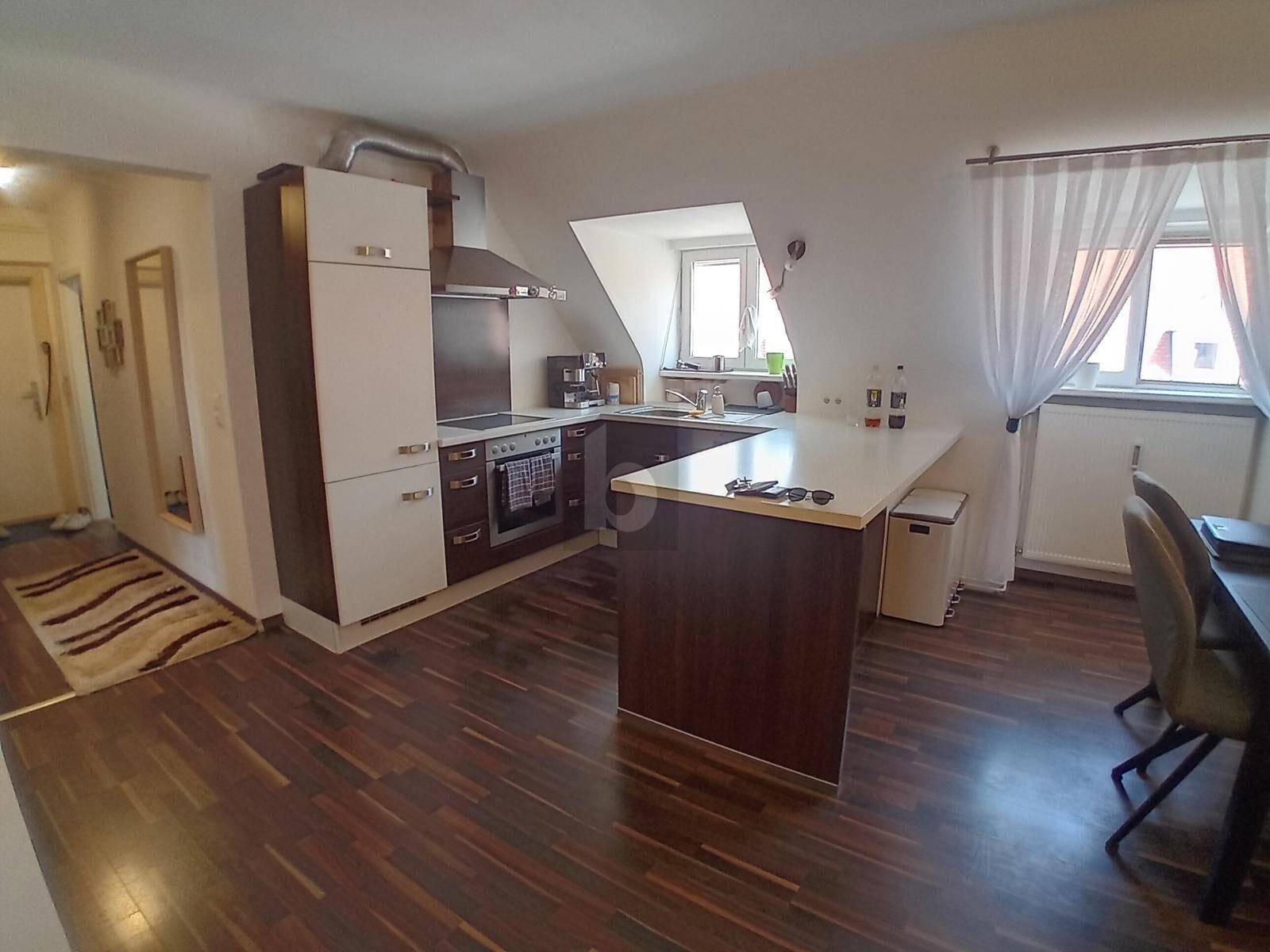 Moderne Küche mit dunklen Holzschränken, heller Arbeitsplatte und integriertem Essbereich am Tresen.