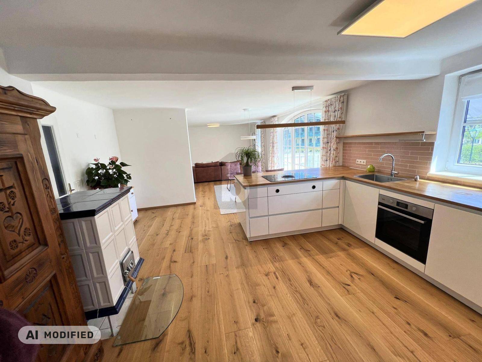 Offener Wohnbereich mit moderner Einbauküche, Holzboden und traditionellem Kachelofen.