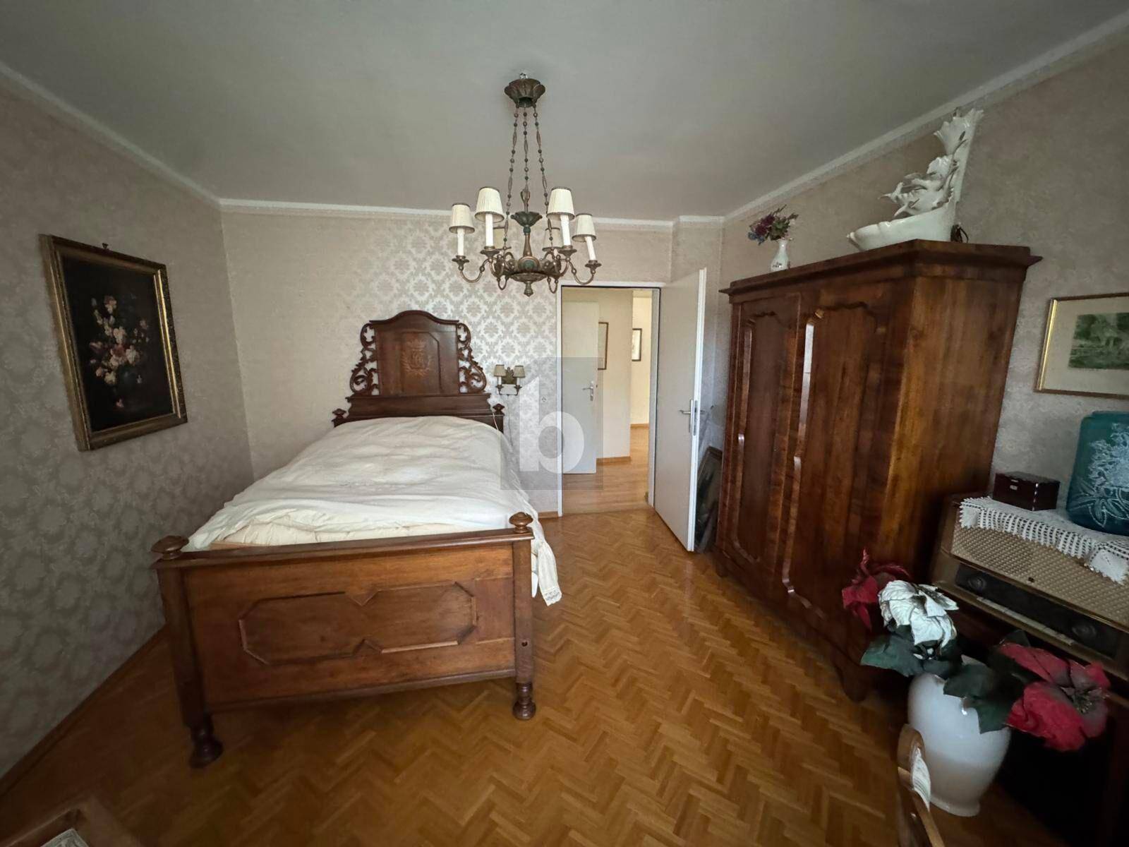 Gemütliches Schlafzimmer mit traditionellem Holzbett, Kleiderschrank und Parkettboden.