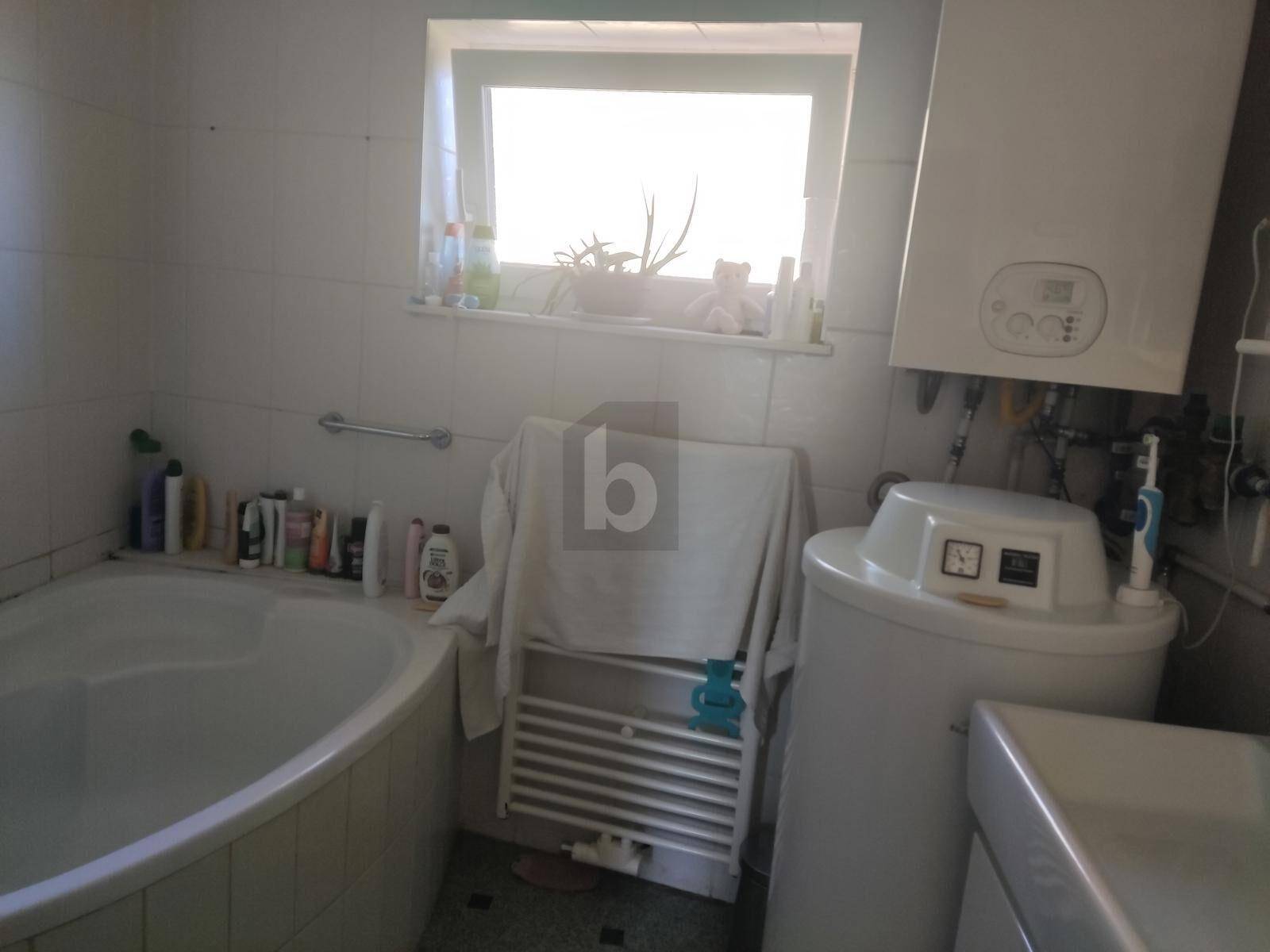 Badezimmer mit Badewanne, Fenster und einem Heizkörper, ausgestattet mit grundlegenden Armaturen.