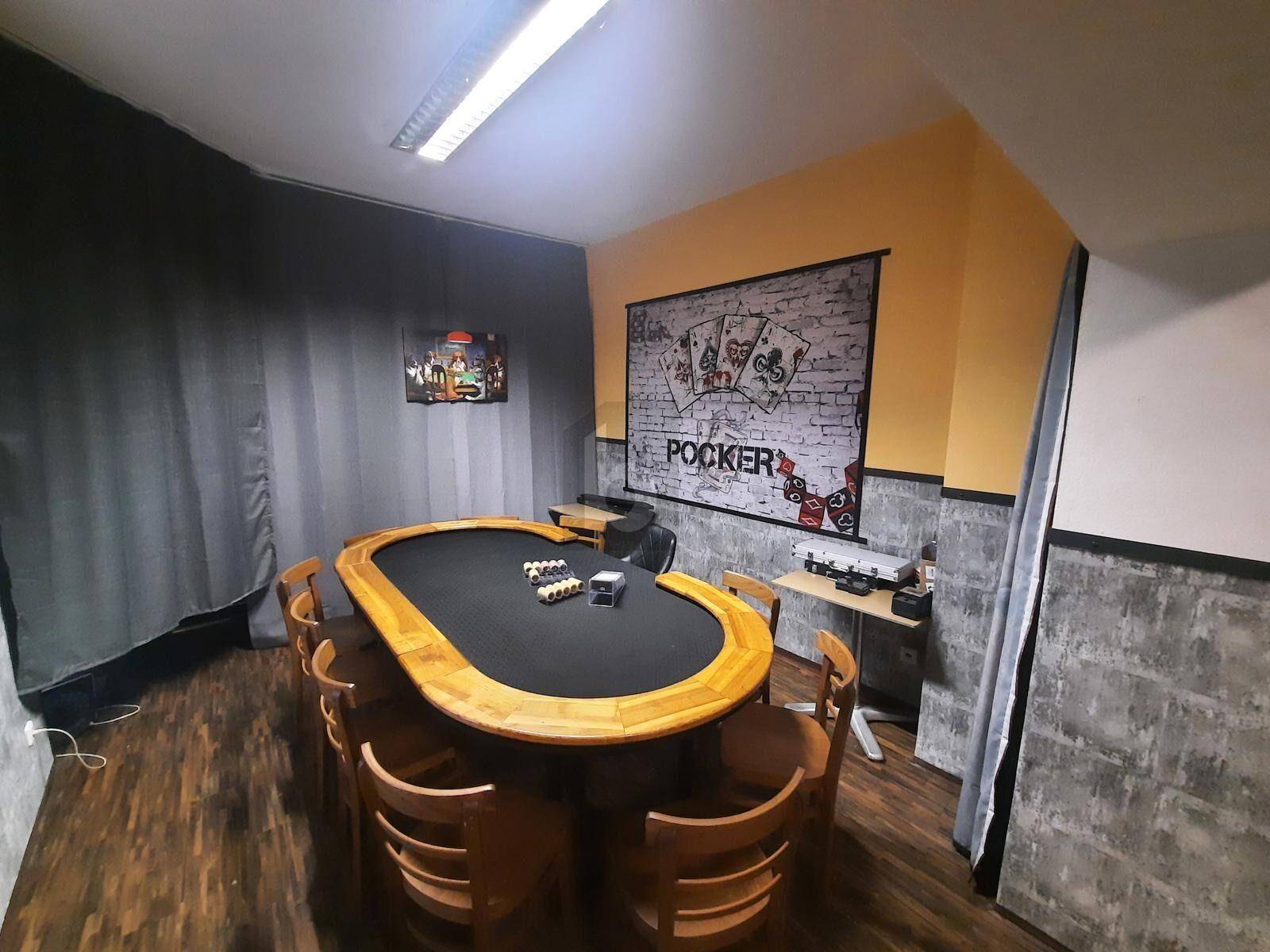 Spielraum mit Pokertisch und Stühlen, dekoriert mit Wandbildern und Vorhängen.