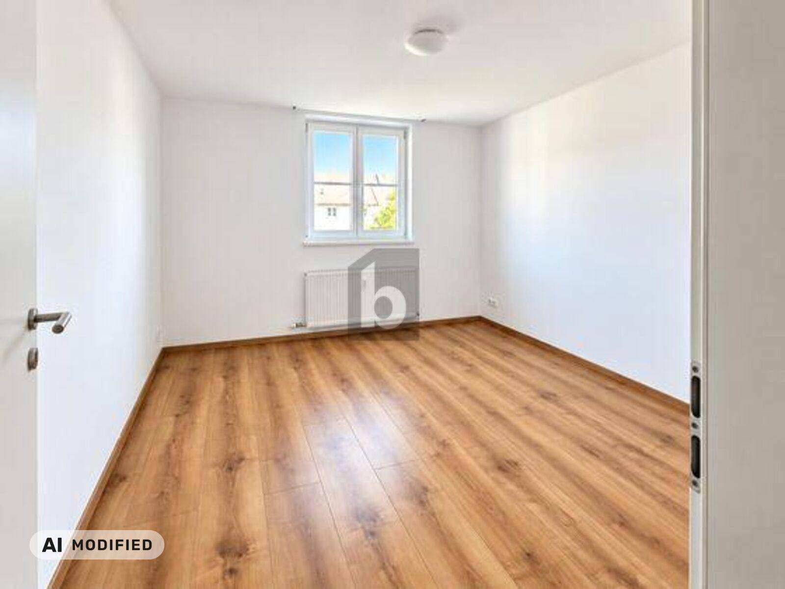 Freundliches Zimmer mit Laminatboden und großem Fenster, bietet viel natürliches Licht.