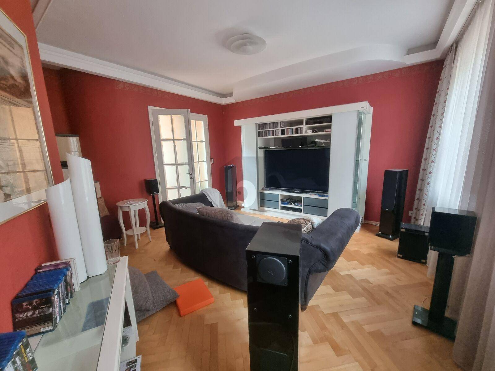 Wohnzimmer mit roten Wänden, Parkettboden und großem Unterhaltungssystem.