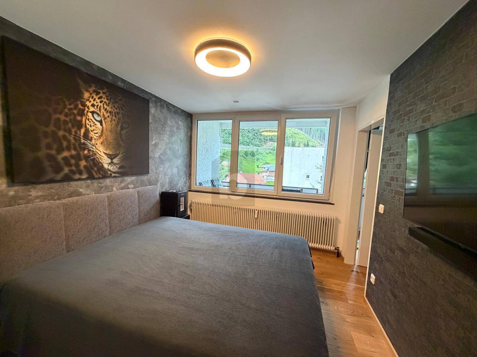 Schlafzimmer mit großem Bett, Holzboden und dekorativer Wandgestaltung.