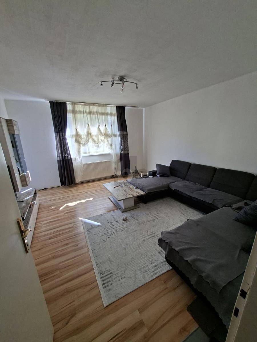 Gemütliches Wohnzimmer mit großem Ecksofa, Couchtisch und Fenster.