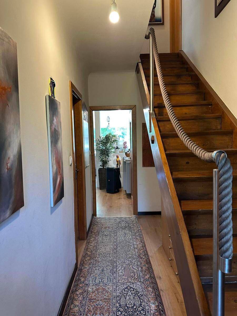 Heller Flur mit Holztreppe und Teppichläufer, der zu weiteren Räumen führt.