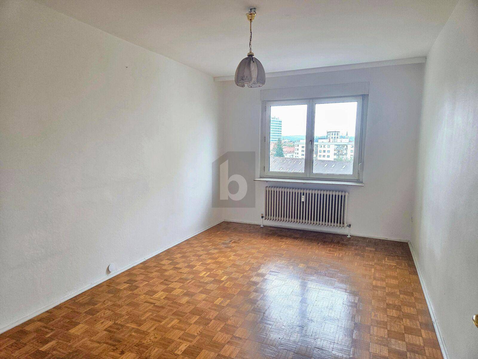 Geräumiges Schlafzimmer mit Parkettboden und Fenster, das viel Tageslicht in den Raum lässt.