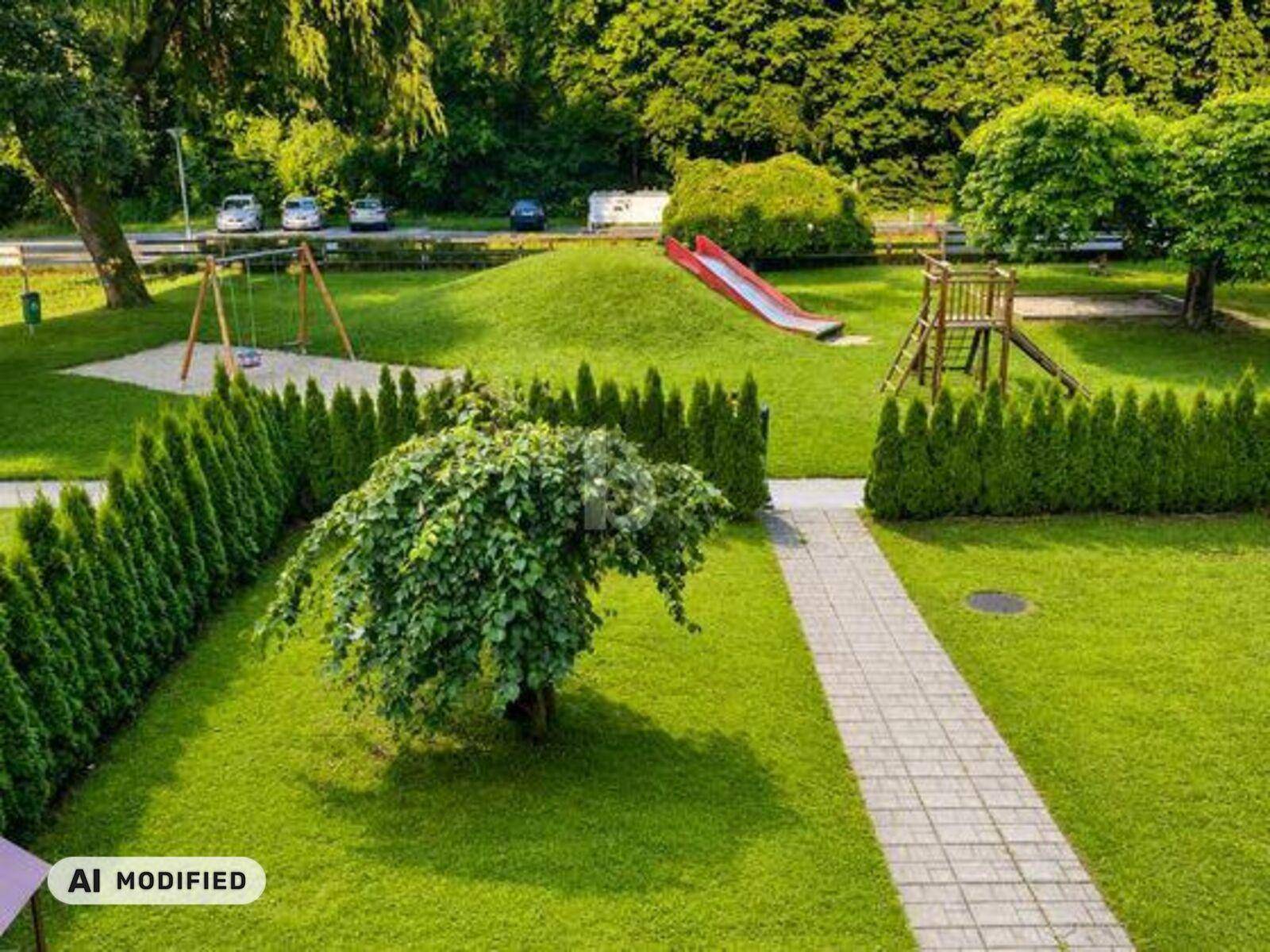 Grüner Gartenbereich mit Kinderspielplatz, Rutsche, Schaukeln und gepflegten Hecken.