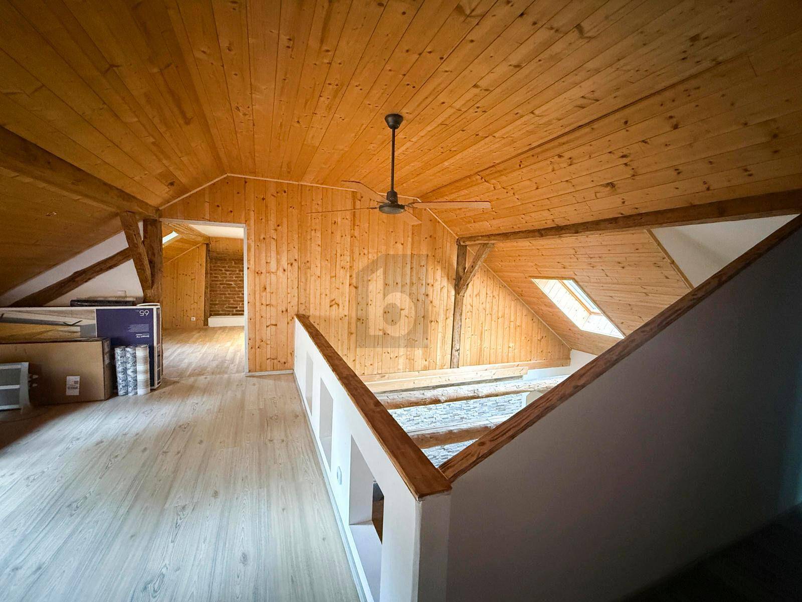 Oberer Galeriebereich mit Holzverkleidung, Dachschrägen, Deckenventilator und natürlichem Lichteinfall.