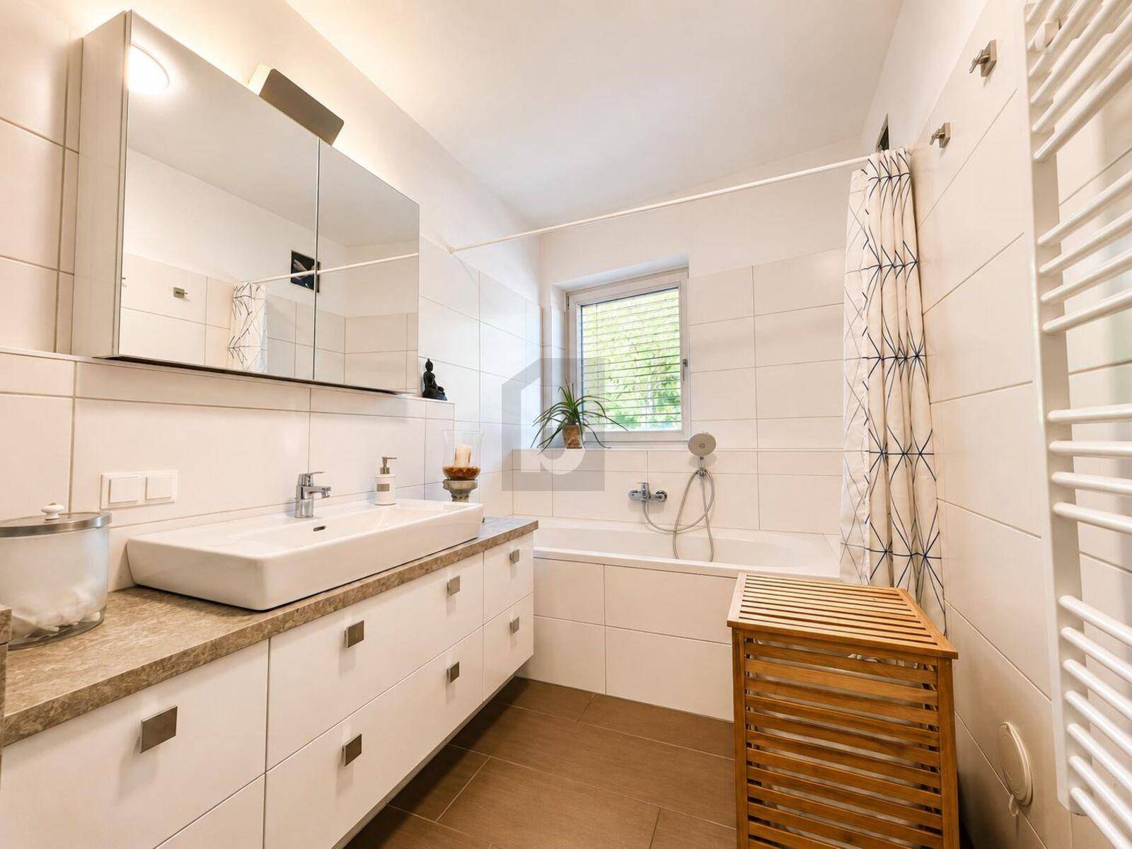 Modernes Badezimmer mit Badewanne, Waschtisch und beheiztem Handtuchhalter.