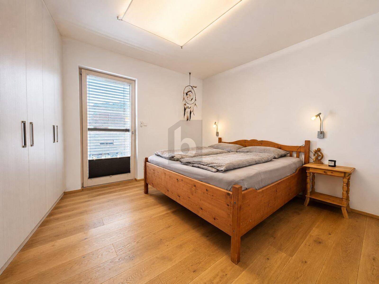 Gemütliches Schlafzimmer mit Holzbett, Einbauschränken und Zugang zum Balkon.