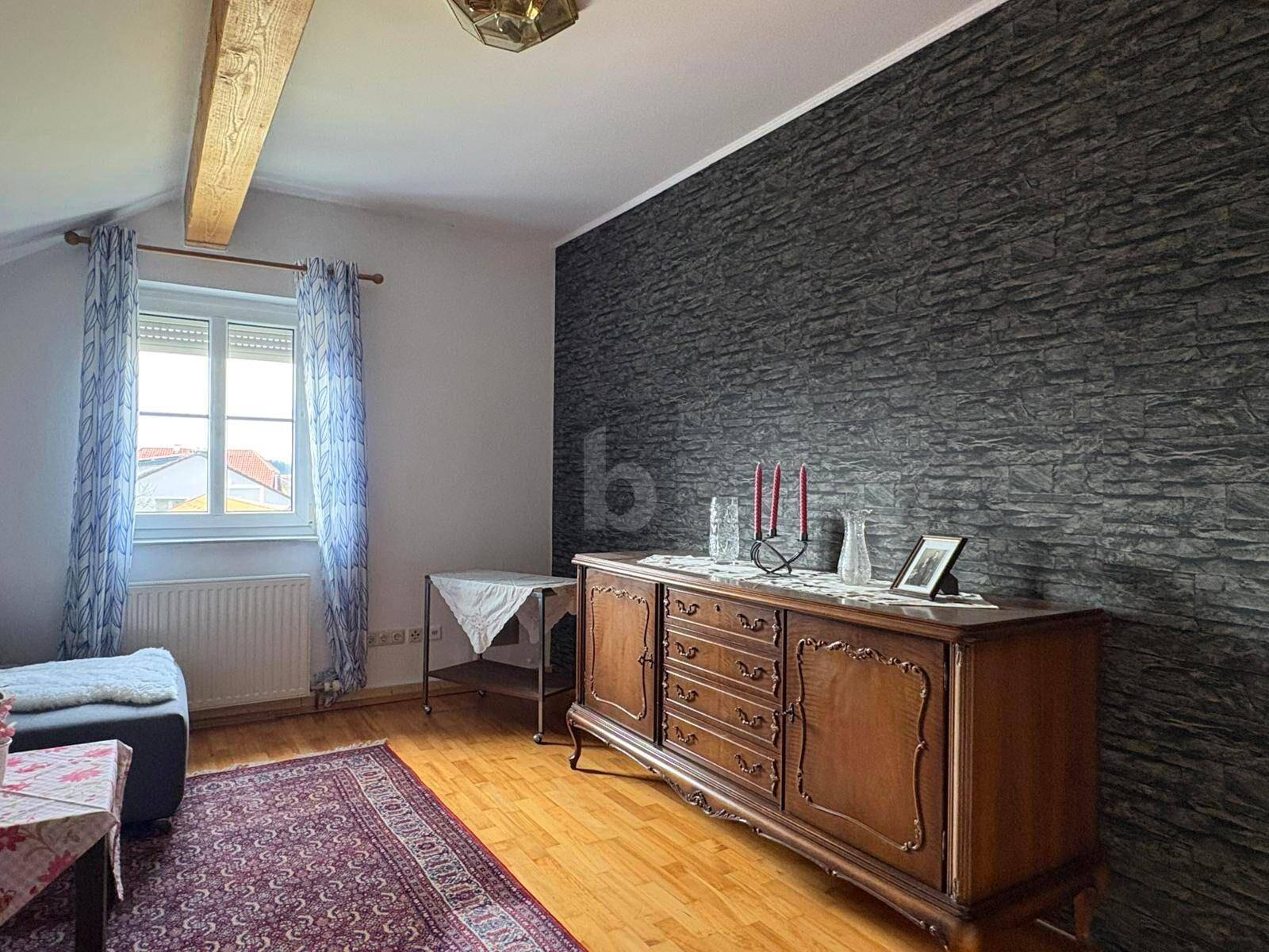 Gemütliches Schlafzimmer mit Holzboden, strukturierter Wand und Dachschräge.