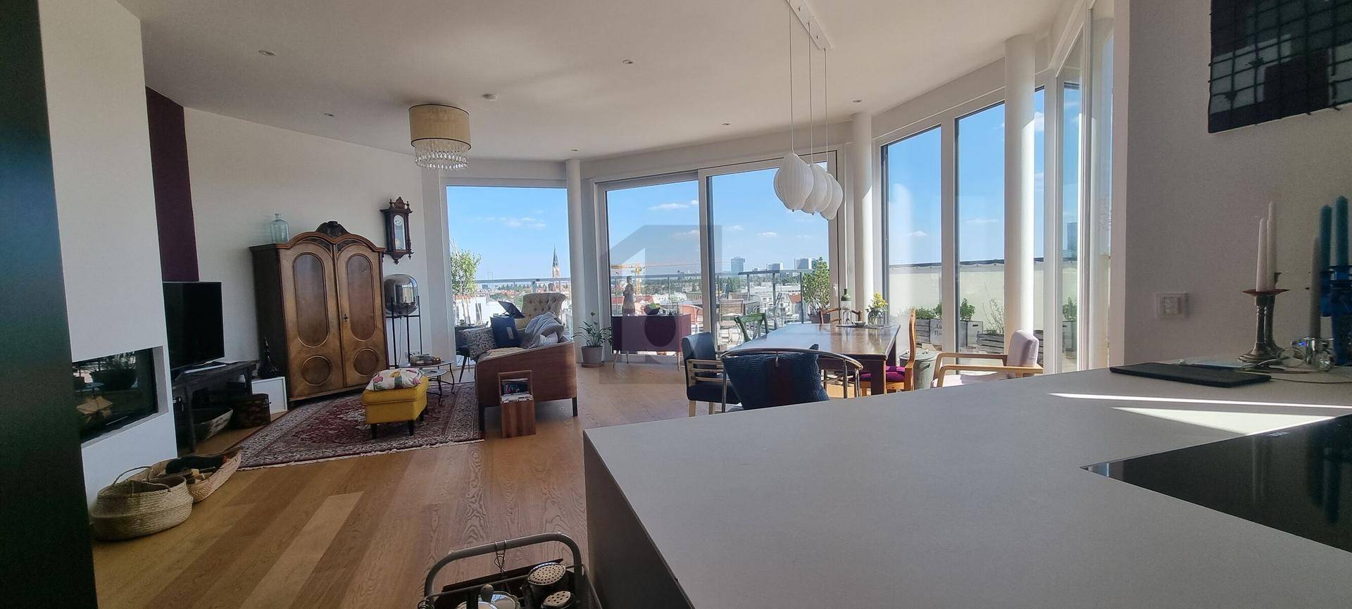 Helles Wohn- und Esszimmer mit großen Fenstern, Holzboden und Panoramablick über die Stadt.