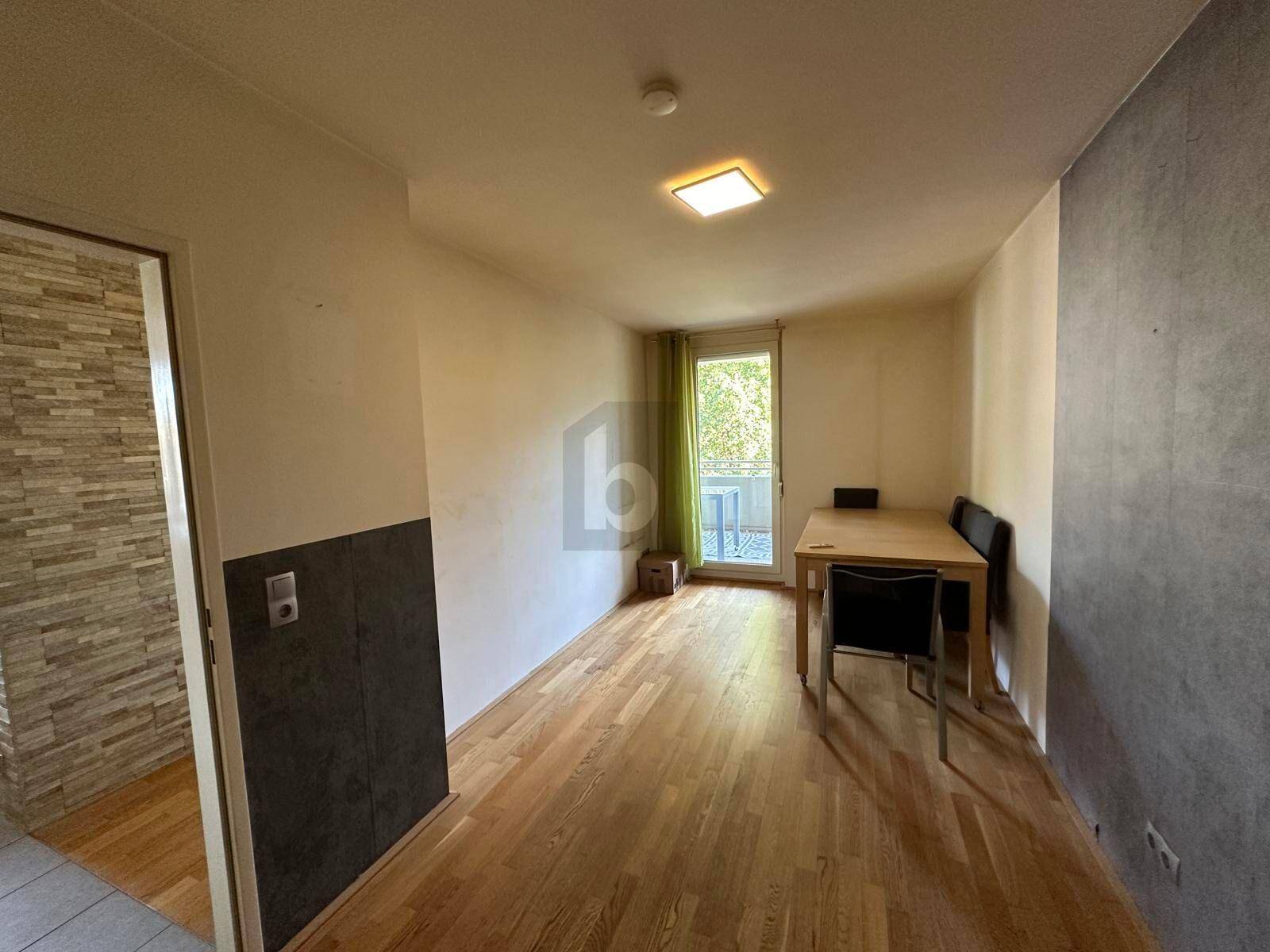 Heller Essbereich mit Holzboden und direktem Zugang zu einem Balkon oder einer Terrasse.